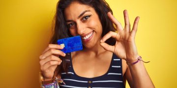 Woman holding her QuicksilverOne Capital One.