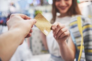 Mulher utilizando cartão, após descobrir o que é bandeira de cartão de crédito.